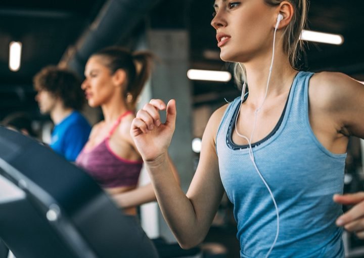 Young people running on a treadmill in health club.